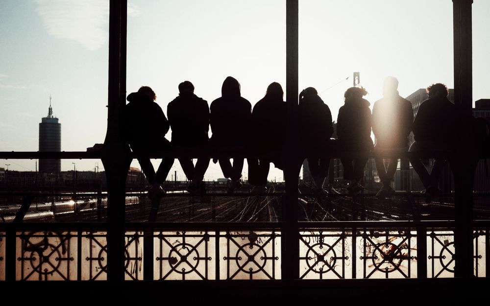 Een groep zit samen op een reling bij zonsondergang