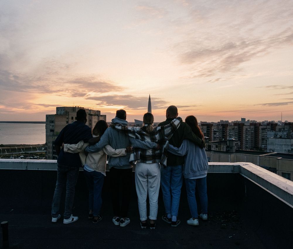 Een groep kijkt bij zonsondergang uit over de stad